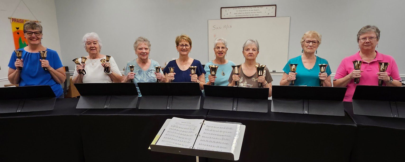 Four women playing handbells in a music room.