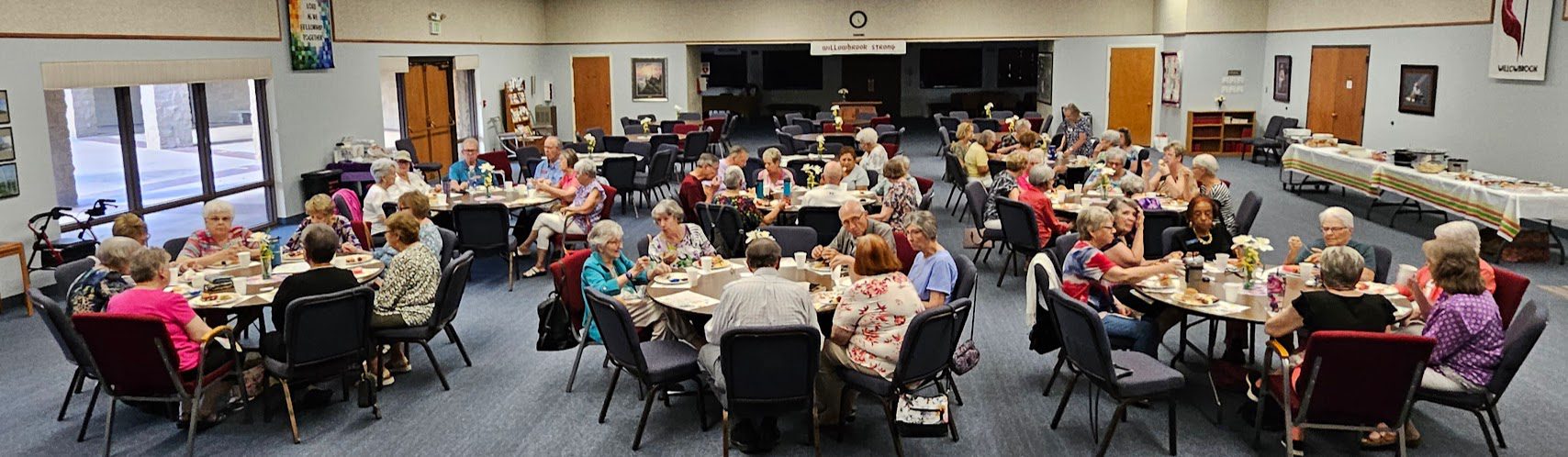 Seniors enjoying a communal meal in a large dining hall.